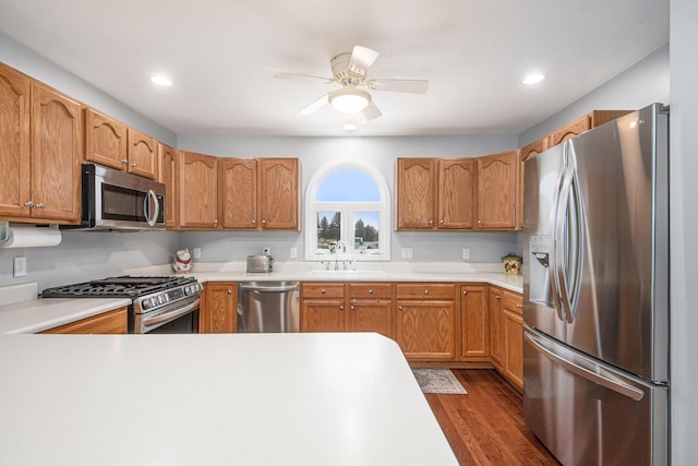 kitchen with ceiling fan, appliances with stainless steel finishes, dark wood-type flooring, light countertops, and a sink