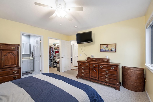 bedroom with a ceiling fan, a spacious closet, a closet, carpet, and ensuite bath