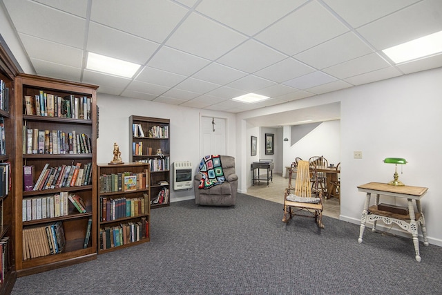 living area with carpet, baseboards, a drop ceiling, and heating unit