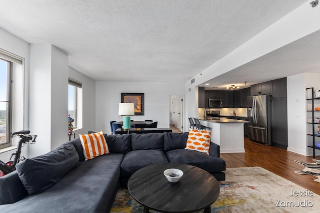 living room with a textured ceiling, dark wood finished floors, and baseboards