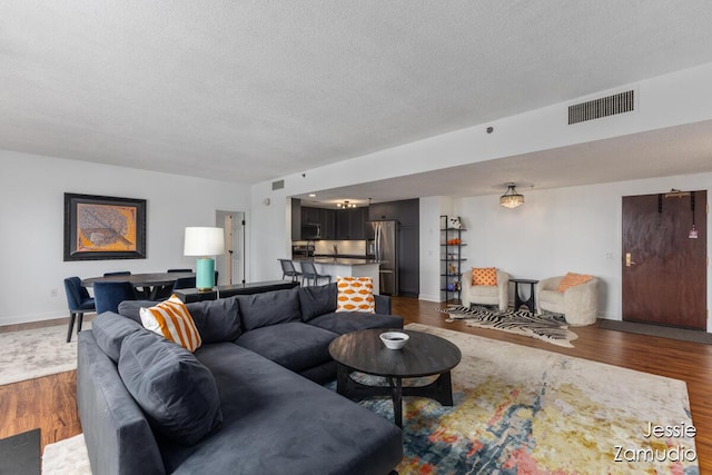 living area featuring visible vents, dark wood finished floors, a textured ceiling, and baseboards