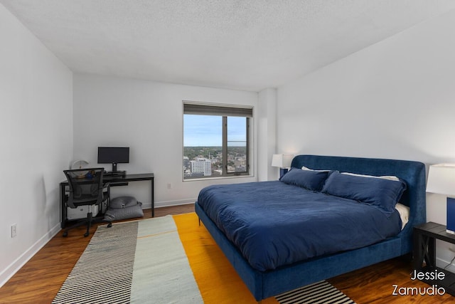 bedroom featuring a textured ceiling, baseboards, and wood finished floors