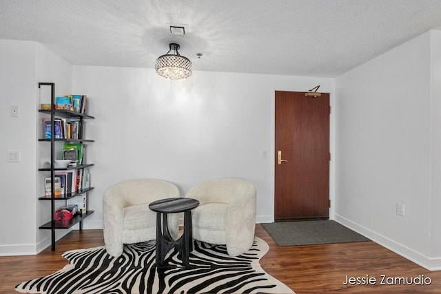 sitting room featuring visible vents, a textured ceiling, and wood finished floors