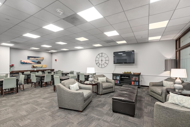 living room featuring carpet floors and a drop ceiling