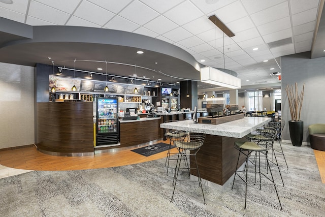 kitchen featuring light wood-style flooring, baseboards, open floor plan, and a drop ceiling