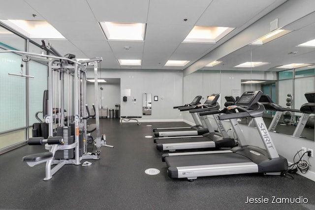 gym with a drop ceiling and baseboards