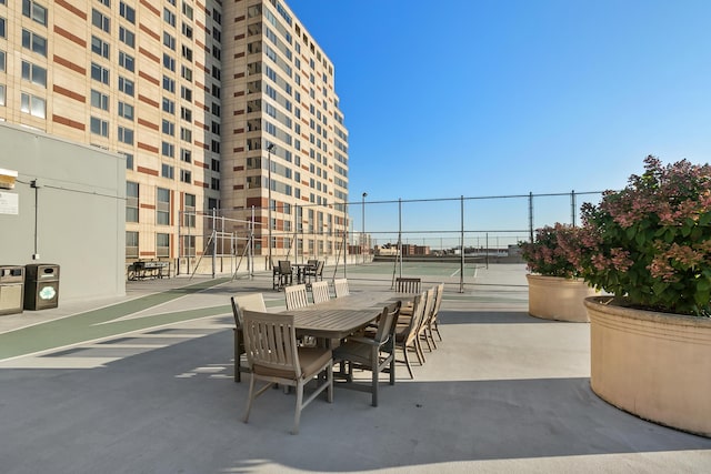 view of patio featuring a tennis court and fence