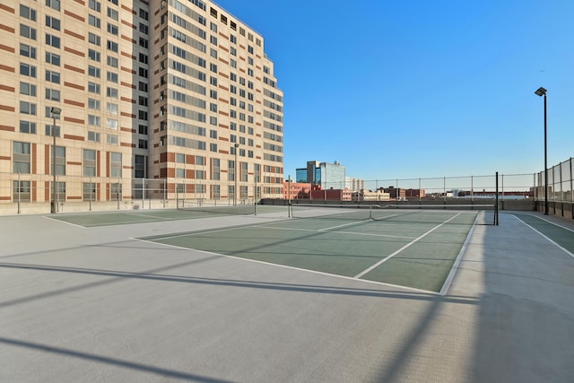 view of tennis court featuring a view of city and fence