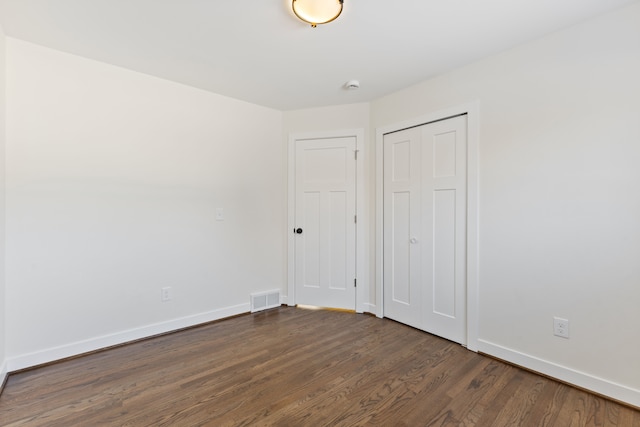 empty room featuring visible vents, dark wood finished floors, and baseboards