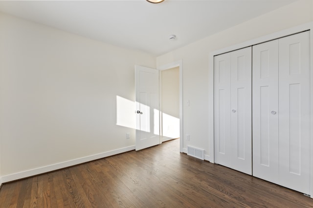 unfurnished bedroom featuring a closet, wood finished floors, visible vents, and baseboards