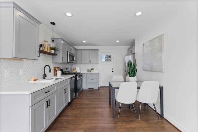 kitchen featuring tasteful backsplash, appliances with stainless steel finishes, gray cabinetry, open shelves, and a sink