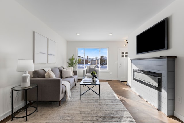 living area featuring recessed lighting, baseboards, wood finished floors, and a glass covered fireplace