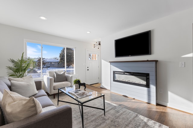 living room with baseboards, a glass covered fireplace, wood finished floors, and recessed lighting