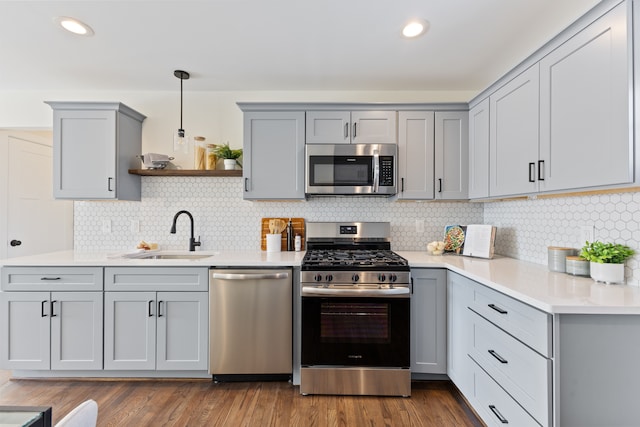 kitchen featuring light countertops, gray cabinetry, appliances with stainless steel finishes, dark wood-type flooring, and a sink