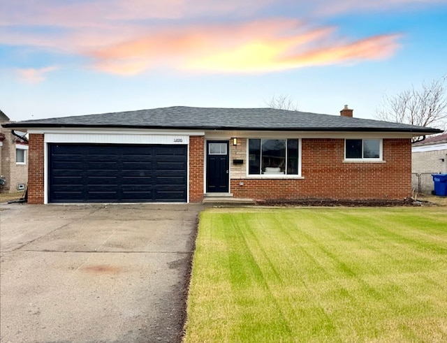 single story home featuring an attached garage, driveway, a front lawn, and brick siding