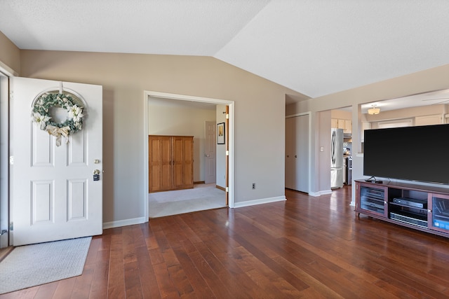 foyer featuring lofted ceiling, dark wood finished floors, and baseboards