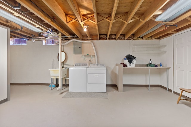 basement with washing machine and clothes dryer, electric panel, and baseboards