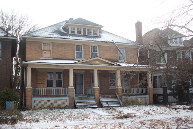 american foursquare style home with covered porch and brick siding