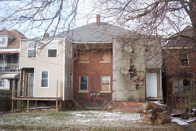 back of house with brick siding and a chimney