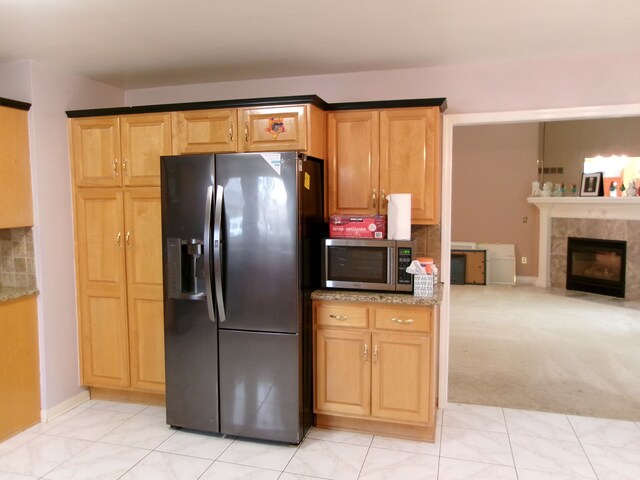 13267 Pearl Dr, Utica, MI 48315 - kitchen with stainless steel microwave, backsplash, black refrigerator with ice dispenser, light stone countertops, and a tile fireplace