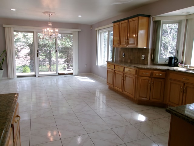 13267 Pearl Dr, Utica, MI 48315 - kitchen featuring baseboards, an inviting chandelier, backsplash, decorative light fixtures, and dark stone counters