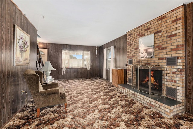 carpeted living area with wooden walls and a fireplace