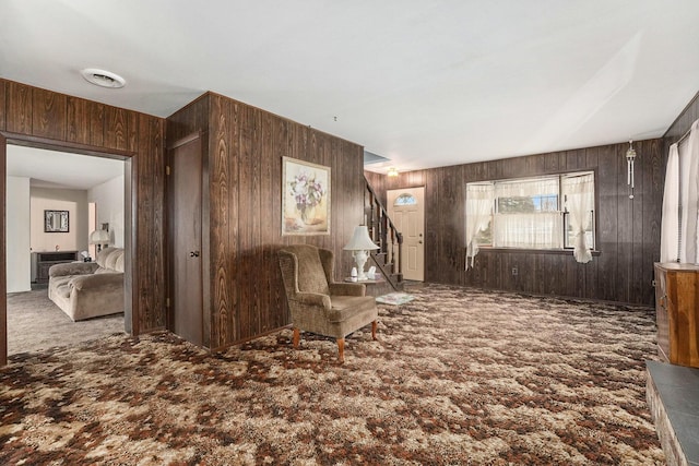 unfurnished room featuring carpet, wooden walls, visible vents, and stairs