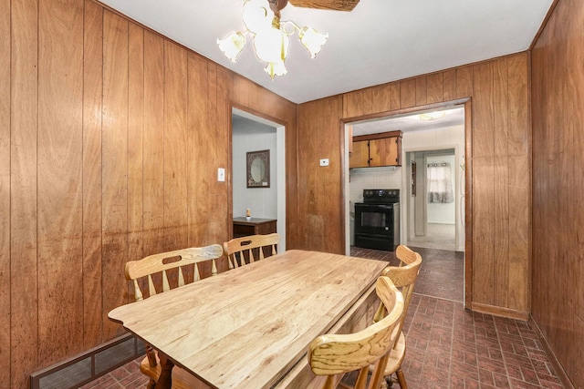 dining room with brick floor, wooden walls, visible vents, and an inviting chandelier