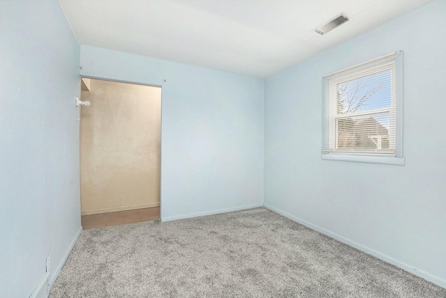 carpeted spare room featuring visible vents and baseboards