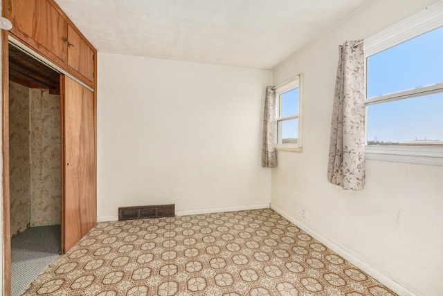 unfurnished bedroom featuring multiple windows, a closet, visible vents, and baseboards