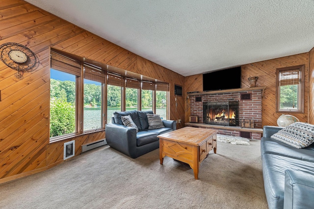 carpeted living area with visible vents, baseboard heating, a textured ceiling, wood walls, and a brick fireplace