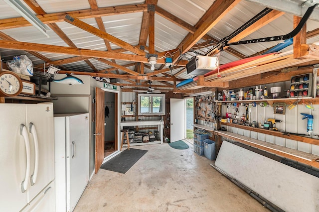 garage with metal wall, freestanding refrigerator, and a garage door opener