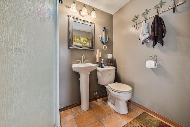 bathroom with toilet, baseboards, a sink, and tile patterned floors