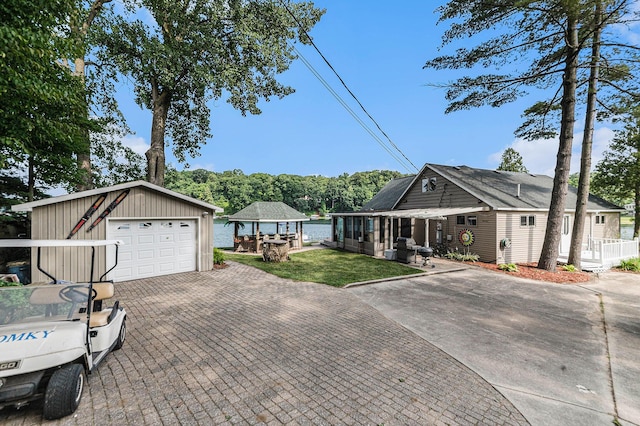 single story home with a garage, a front lawn, decorative driveway, and an outbuilding