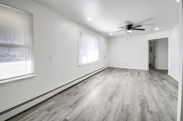 spare room with plenty of natural light, baseboard heating, and light wood-style flooring