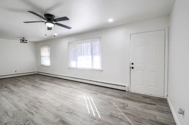 spare room featuring a baseboard radiator, baseboards, ceiling fan, and wood finished floors