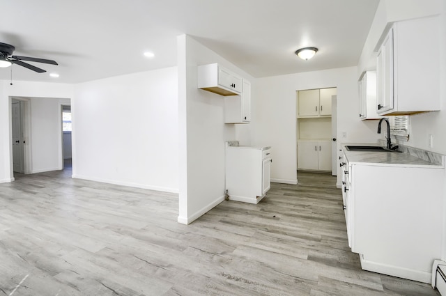 kitchen with light wood-type flooring, baseboard heating, a sink, and open floor plan