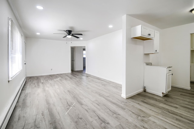 empty room with a baseboard heating unit, recessed lighting, light wood-type flooring, and baseboards