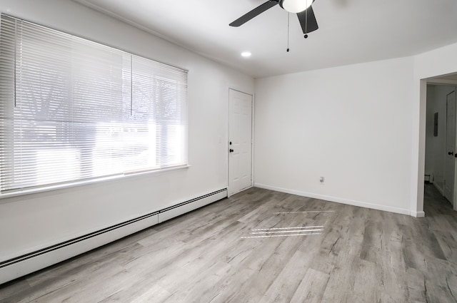 empty room with a baseboard radiator, ceiling fan, baseboards, and wood finished floors