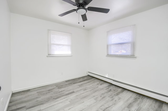 unfurnished room featuring a baseboard heating unit, wood finished floors, and baseboards