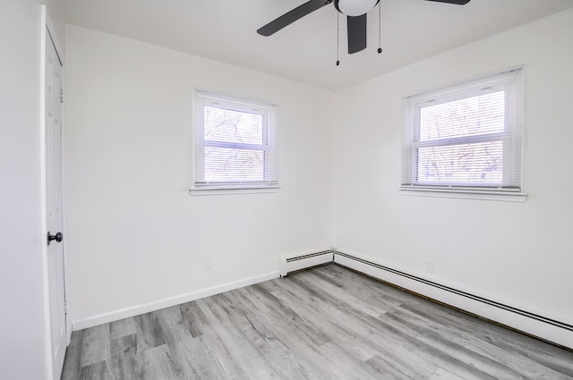 spare room with a healthy amount of sunlight, light wood-style flooring, baseboards, and baseboard heating