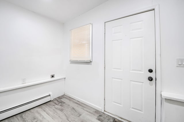 interior space featuring a baseboard heating unit, laundry area, baseboards, light wood finished floors, and electric dryer hookup