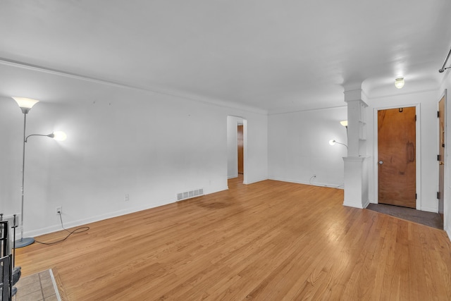 unfurnished living room featuring ornate columns, light wood-style flooring, visible vents, and baseboards