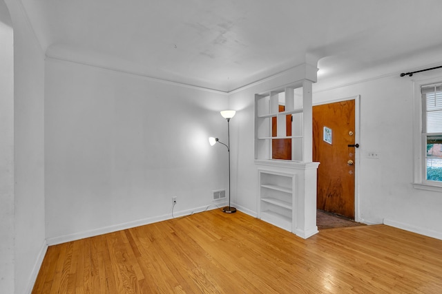 unfurnished room featuring baseboards, wood finished floors, visible vents, and built in features