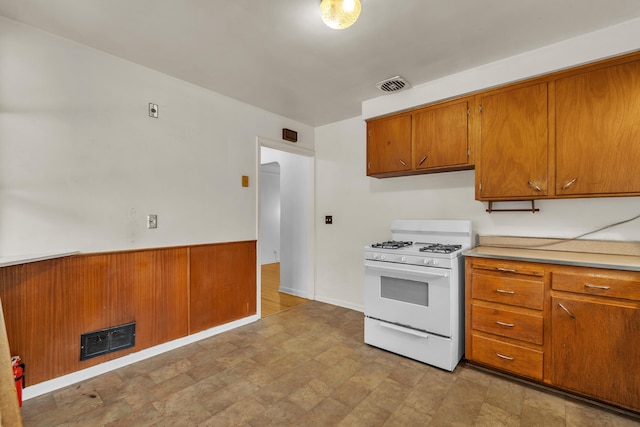 kitchen with white gas range, visible vents, brown cabinets, and light countertops