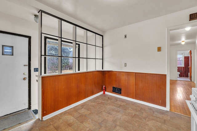 clothes washing area featuring a wainscoted wall, visible vents, and wood walls