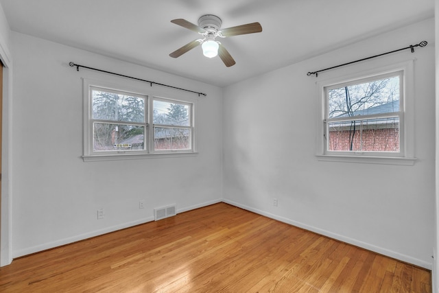 empty room with light wood-type flooring, a healthy amount of sunlight, baseboards, and visible vents