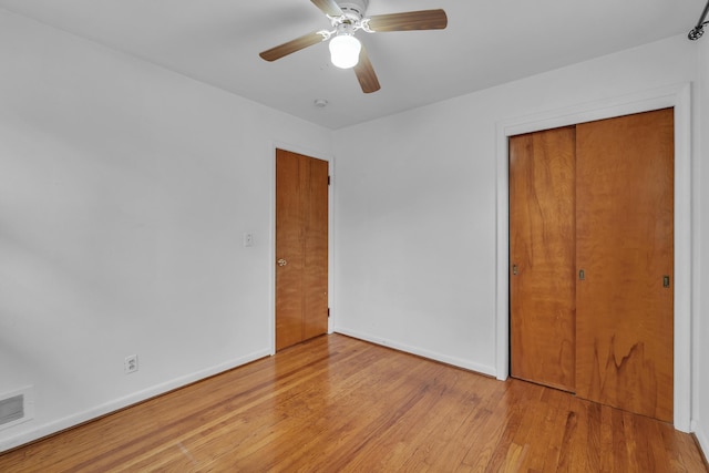 unfurnished bedroom with light wood finished floors, a closet, visible vents, a ceiling fan, and baseboards