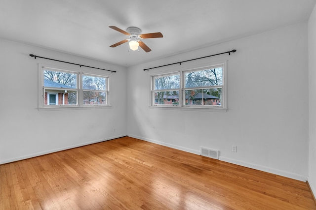 spare room featuring baseboards, ceiling fan, visible vents, and light wood-style floors