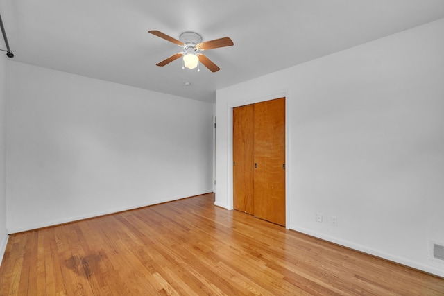 unfurnished room featuring ceiling fan, wood finished floors, visible vents, and baseboards